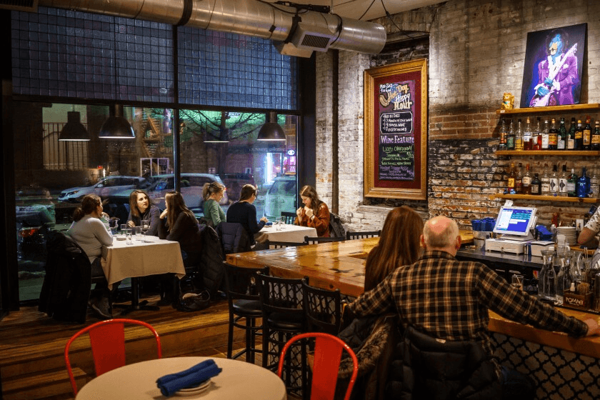 Bleu Duck dining room with exposed brick and Prince portrait
